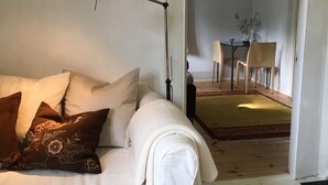 A room with a white sofa, a black floor lamp, and a dining area with a table and chairs.