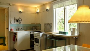 A compact kitchen with a sink, stove, and a window with a view of greenery.