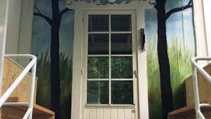 A white door with a window, flanked by white railings and a wooden staircase.