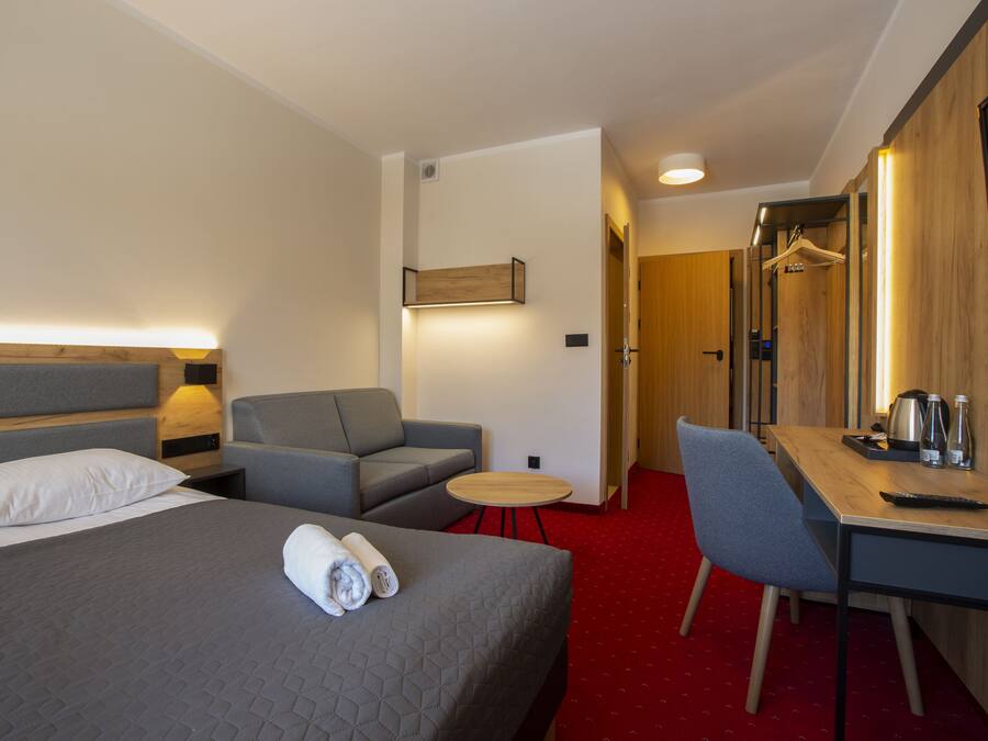 Una habitación de hotel con cama, sofá, escritorio y televisor.