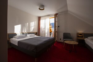 Habitación de hotel con una cama grande, una silla, una mesita y vistas al exterior.