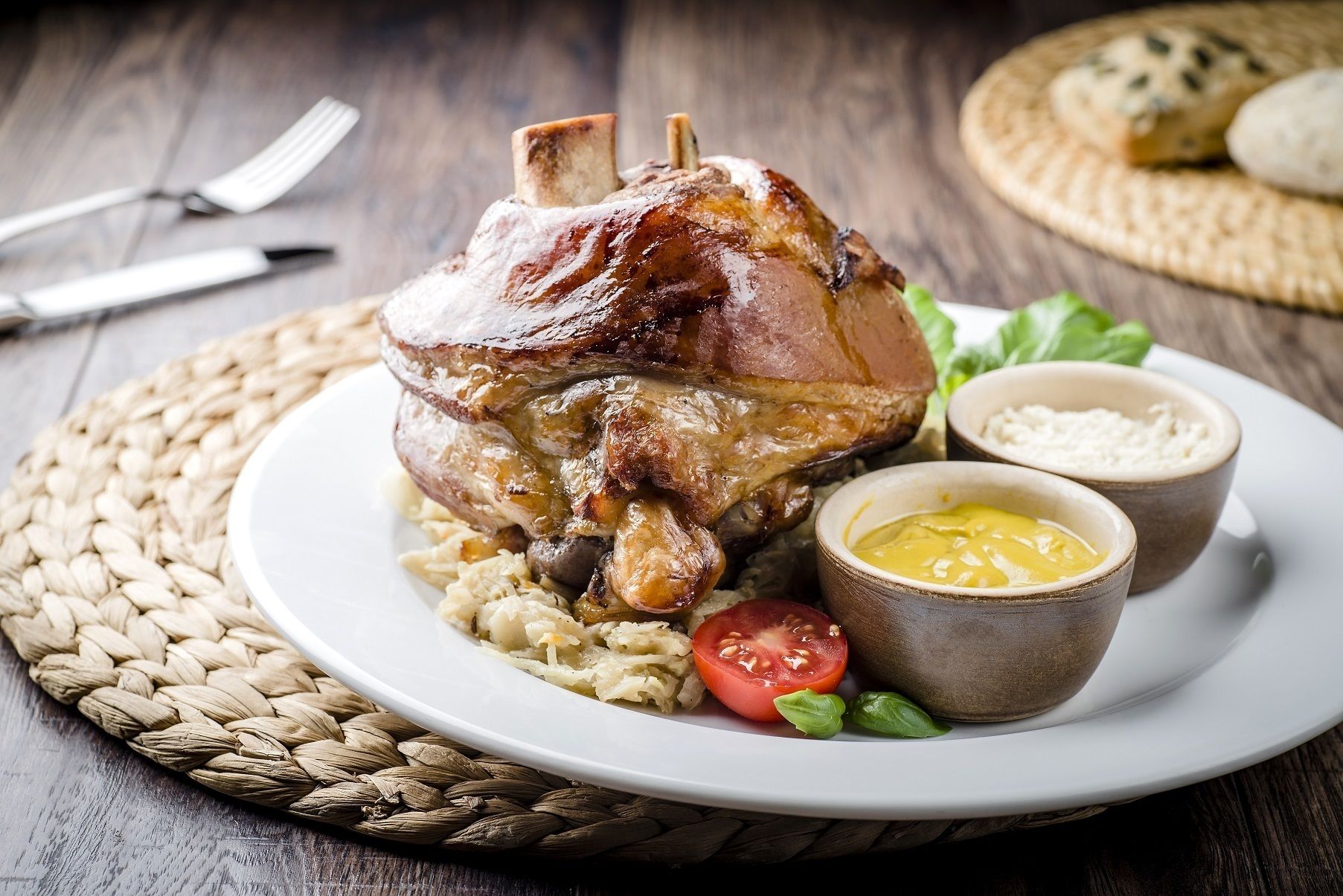A roasted ham with mustard and sauerkraut on a plate.