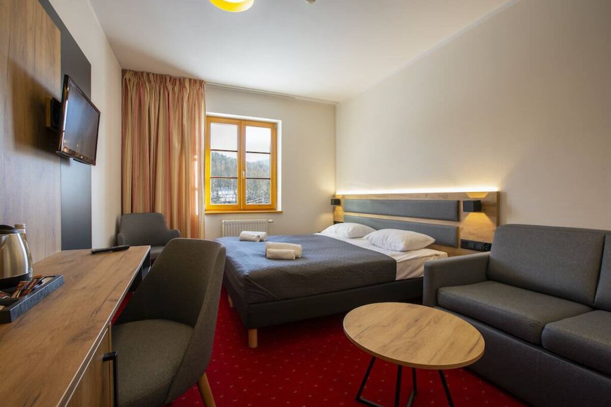 Ein Hotelzimmer mit einem Bett, einem Schreibtisch, einem Sessel, einer Couch und einem kleinen runden Tisch.