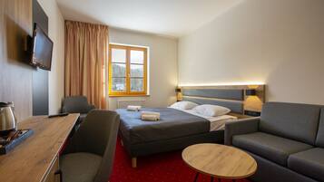 Una habitación de hotel con cama, escritorio, silla, sofá y una pequeña mesa redonda.