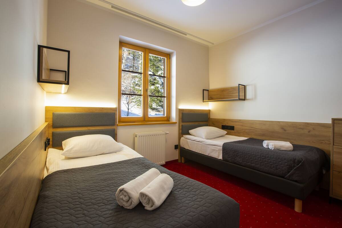 Ein Hotelzimmer mit zwei Betten, einem Fenster und einer Heizung.