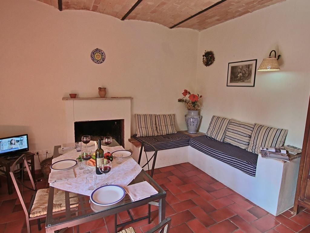 A cozy living room with a fireplace, a sofa, a dining table set for two, and a television.