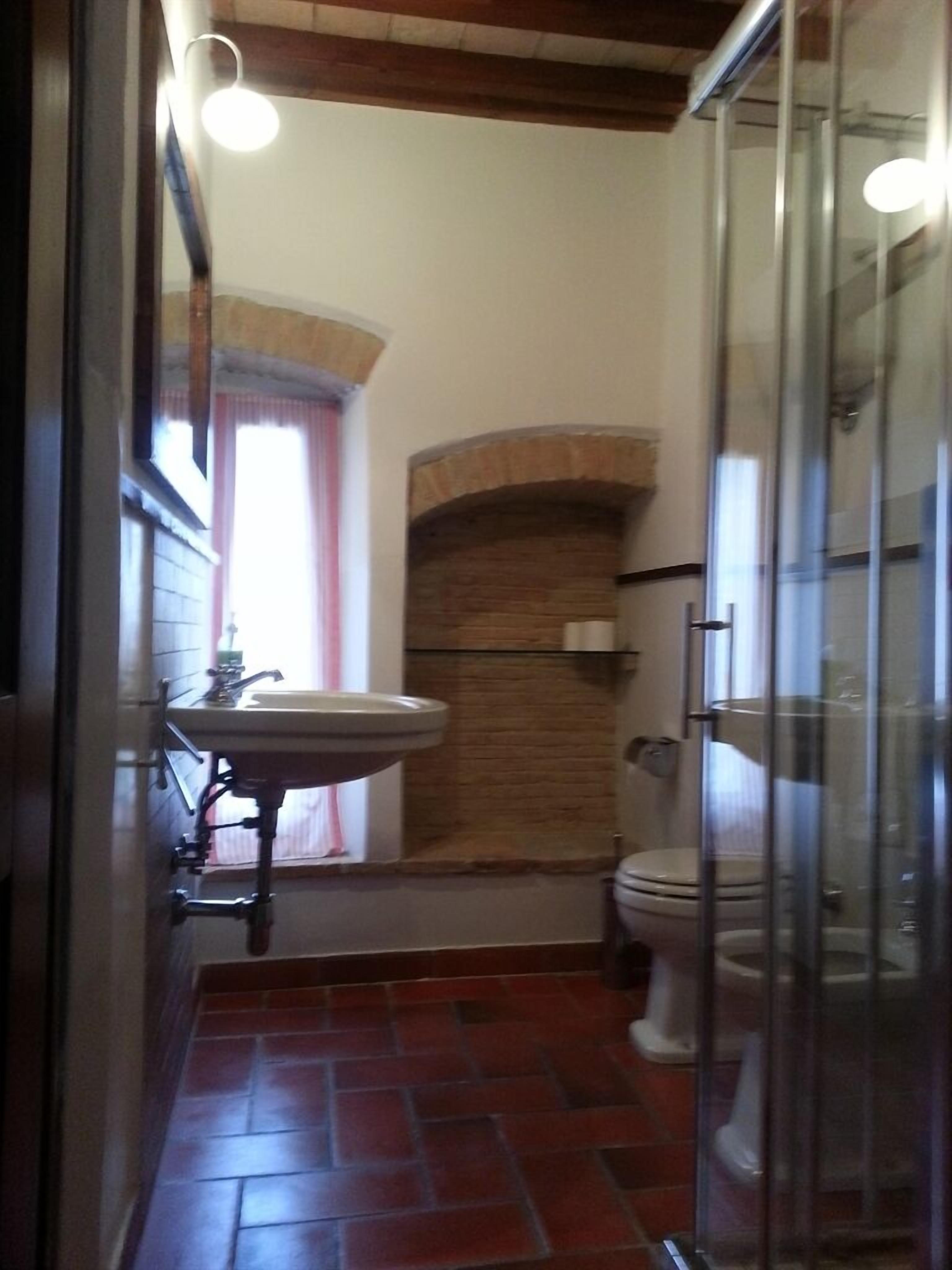 A bathroom with a sink, toilet, and glass shower enclosure.