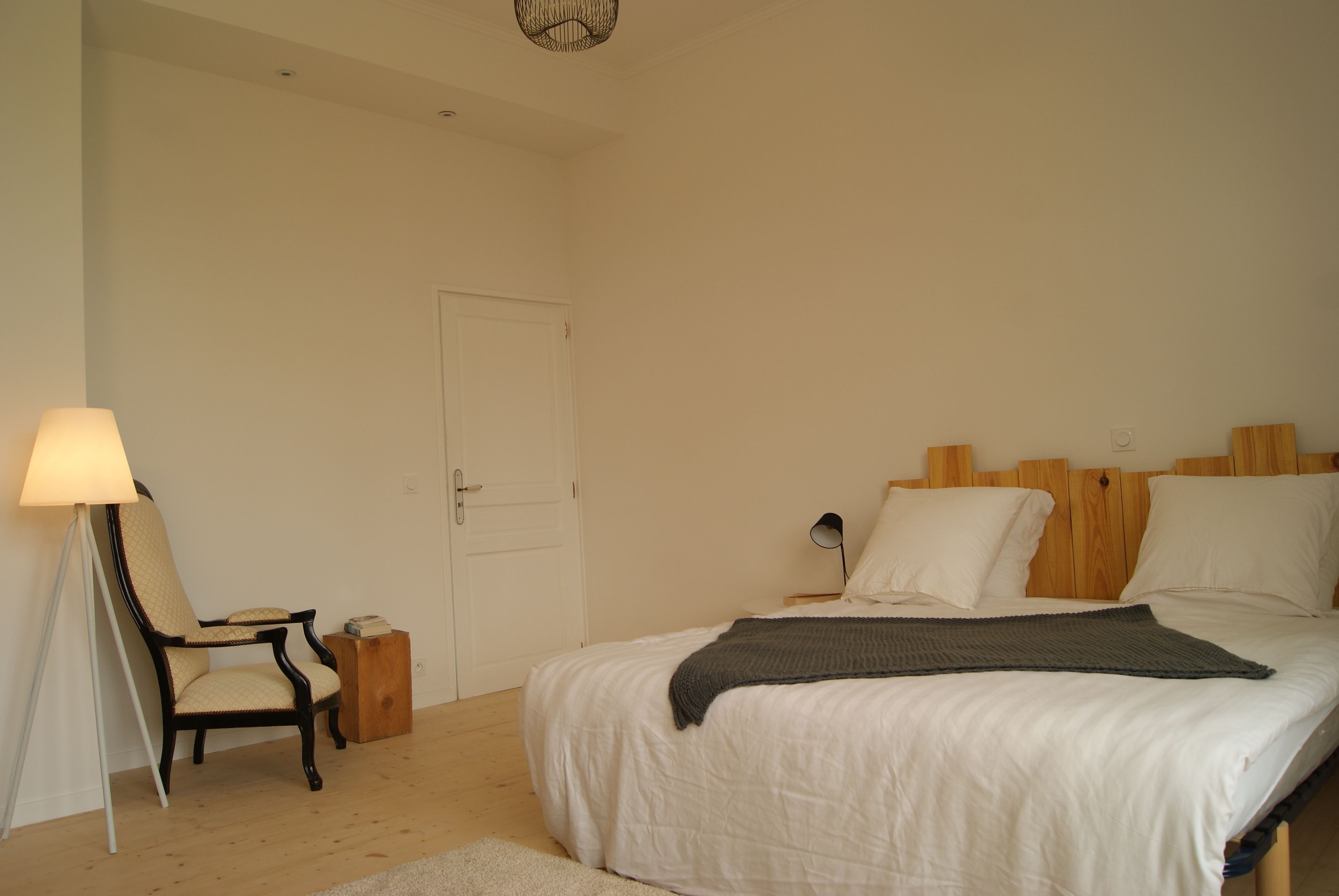Ein Schlafzimmer mit Bett, Stuhl, Lampe und Tür.