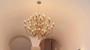Una gran escalera con un candelabro, una silla roja y una planta en maceta.