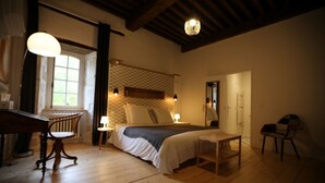 Un dormitorio acogedor con suelo de madera, una cama con cabecero texturizado, un escritorio con silla y una ventana con cortinas.