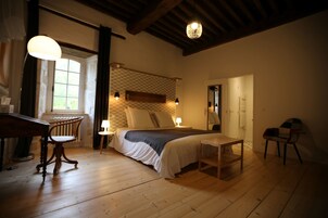 Un dormitorio acogedor con suelo de madera, una cama con cabecero texturizado, un escritorio con silla y una ventana con cortinas.