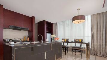 A modern kitchen with dark cabinetry, a central island, and a dining area with a table and chairs.