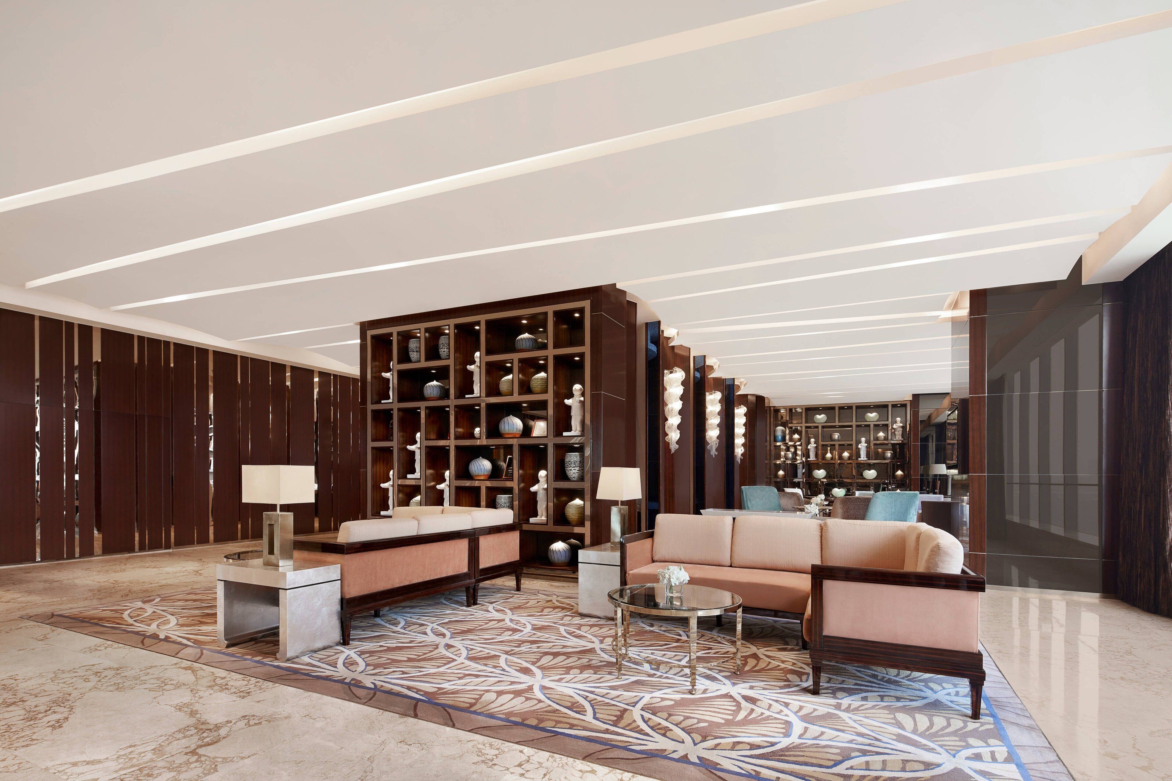 A modern lobby with a sofa, coffee table, and a large bookshelf filled with decorative items.