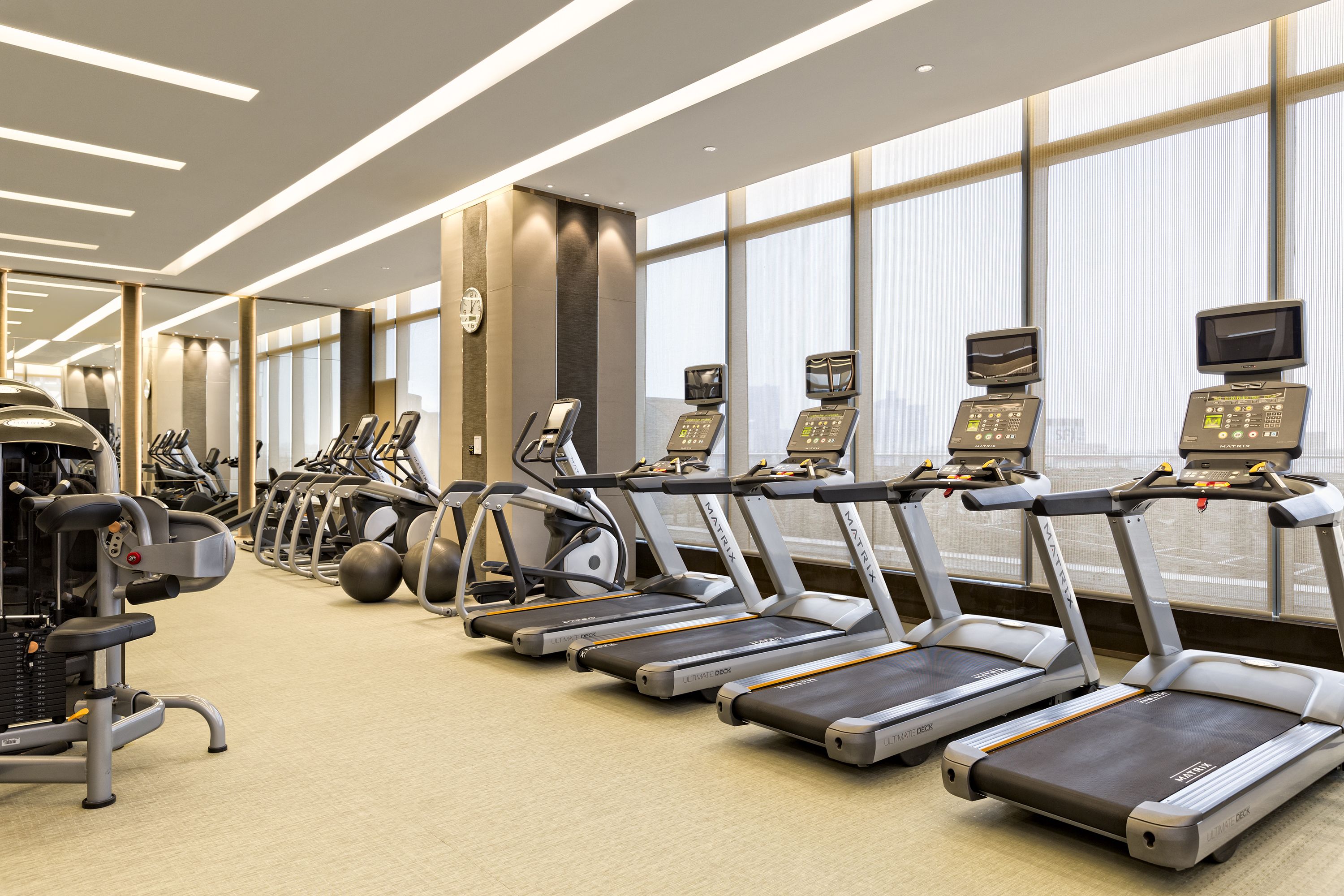 Un gimnasio con cintas de correr, bicicletas estáticas y máquinas de pesas.