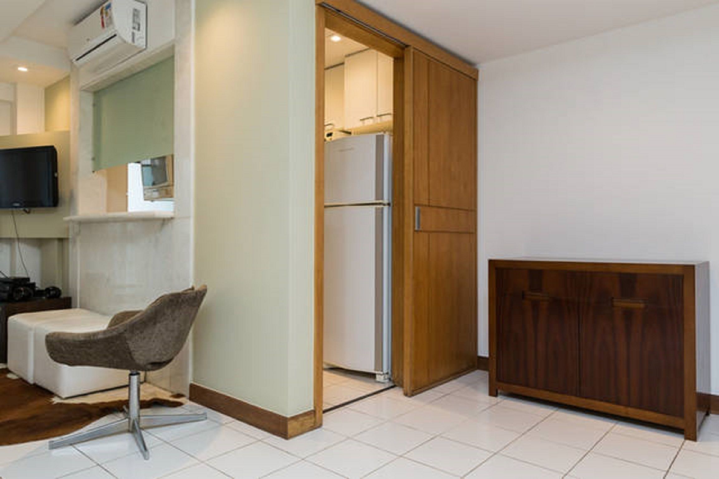A modern room with a white sofa, a wooden cabinet, and a television mounted on the wall.