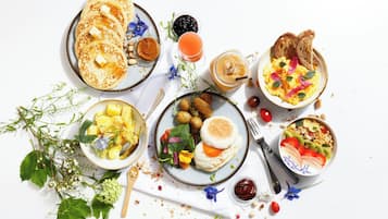 En frukostbuffé med pannkakor, äggröra, rostat bröd samt olika sorters frukt och grönsaker.