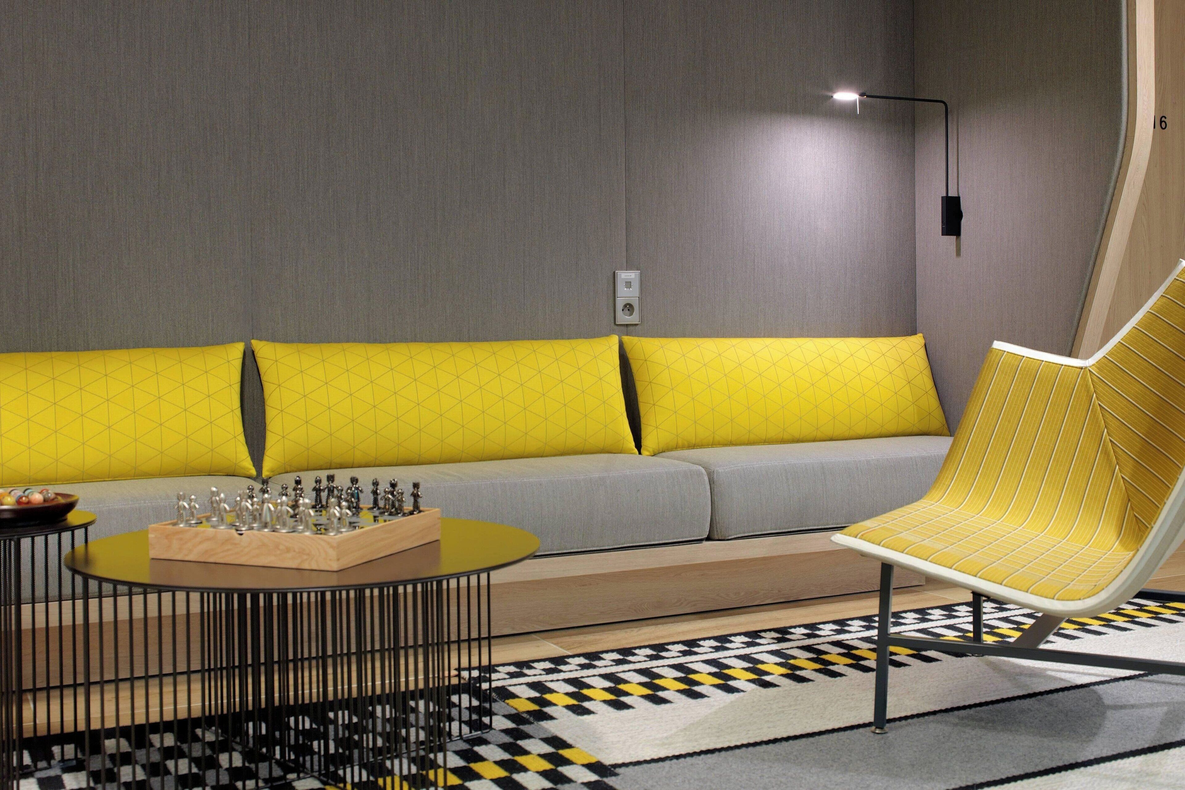 A modern living room with a sofa, a yellow armchair, a coffee table, and a chess set.