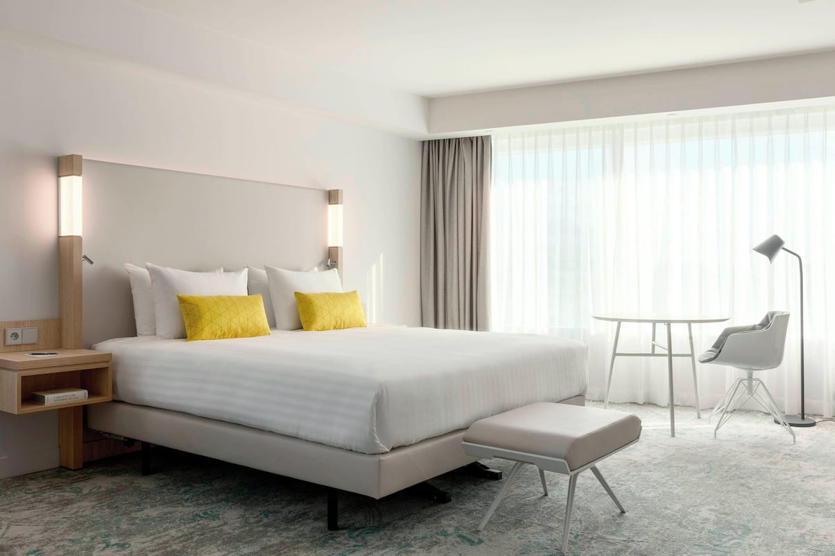 Une chambre d’hôtel moderne avec un grand lit, des tables de chevet, un bureau et une chaise.