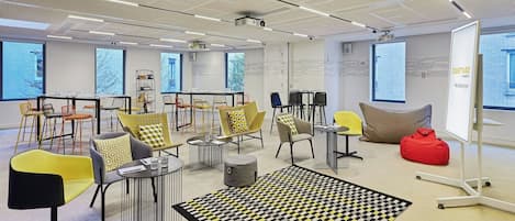 Un espacio de oficina moderno con una variedad de opciones de asientos, incluyendo sillas y mesas, y una alfombra grande con diseño en el suelo.