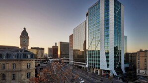 A modern building with a glass facade and a clock tower in the background. - Courtyard by  Marriott Paris Gare de Lyon (Paris)