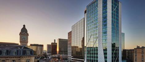 A modern building with a glass facade and a clock tower in the background.