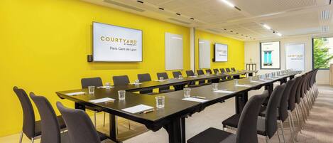 A conference room with a long table, chairs, and a bright yellow wall.