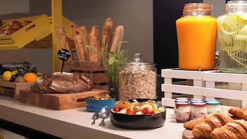 A breakfast buffet with bread, pastries, fruits, and various spreads.