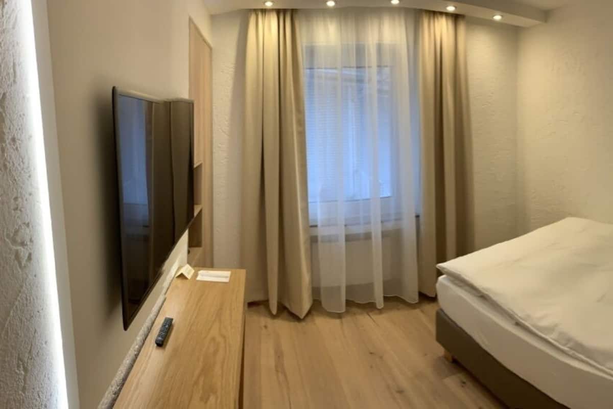 Une chambre d’hôtel avec un lit, une télévision et une fenêtre avec des rideaux.