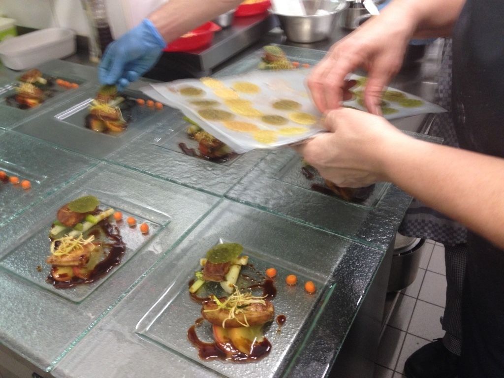 Une personne prépare des aliments sur un plan de travail en verre, avec différents plats et ingrédients à portée de main.