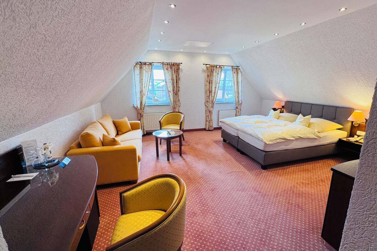 Une chambre d’hôtel comprenant un lit, un canapé, une chaise, une petite table et un bureau.
