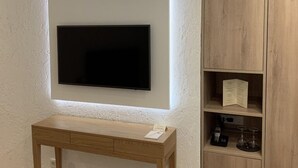 Une pièce équipée d’un téléviseur fixé au mur, d’un bureau en bois et d’une armoire en bois avec des étagères.