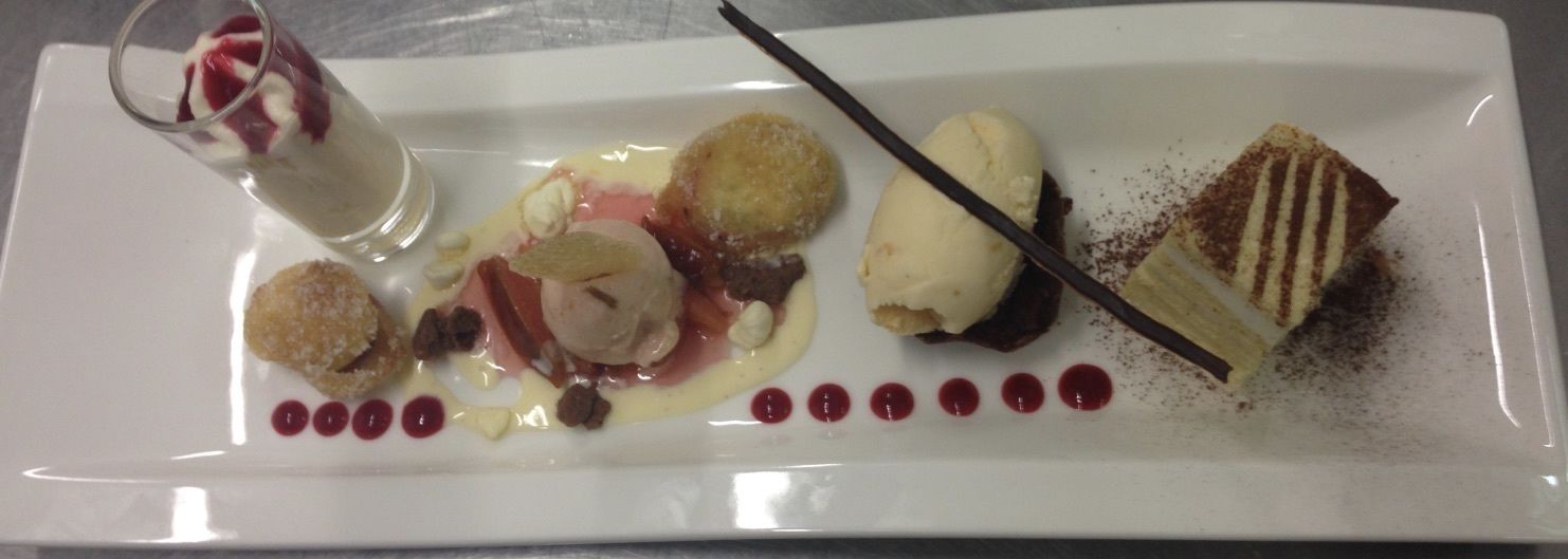 Un plato de postres con diversos elementos, incluyendo un vaso de bebida dulce, helado y una porción de pastel.