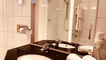 Un baño moderno con un lavabo negro, un espejo, una ducha y un secador de pelo.
