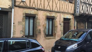 Une rue étroite bordée d’un bâtiment dont les murs en pierre et la charpente en bois sont apparents.