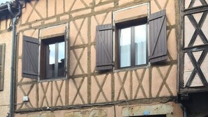 Un fourgon noir était garé devant un bâtiment dont la charpente en bois était apparente et qui présentait une façade en pierre.