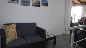 Un salón con un sofá gris, una mesa de centro con revistas, y una pared decorada con fotografías de paisajes.