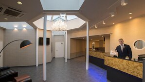 A hotel reception area with a modern design, including a reception desk, seating area, and a chandelier. - Eurostrand Resort Lüneburger Heide (Fintel)
