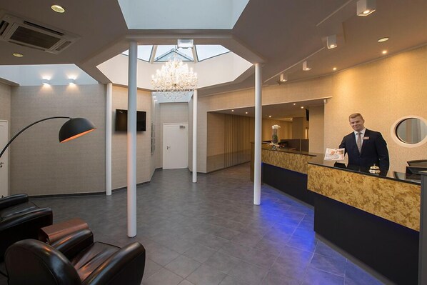 A hotel reception area with a modern design, including a reception desk, seating area, and a chandelier. - Eurostrand Resort Lüneburger Heide (Fintel)