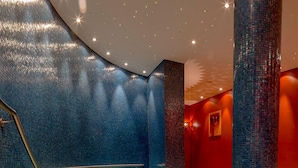 A modern interior with a blue-tiled wall, a red accent wall, and a seating area with a mosaic floor. - Eurostrand Resort Lüneburger Heide (Fintel)
