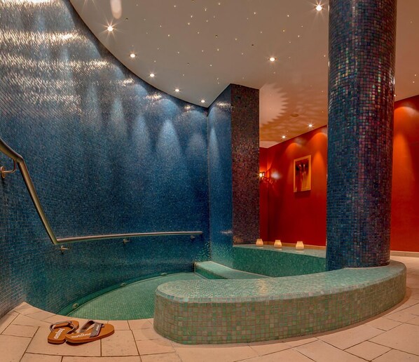 Un interior moderno con una pared azul de azulejos, un muro de acento rojo y una zona de estar con suelo de mosaicos.