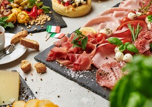 A charcuterie board with various meats, cheeses, and garnishes.