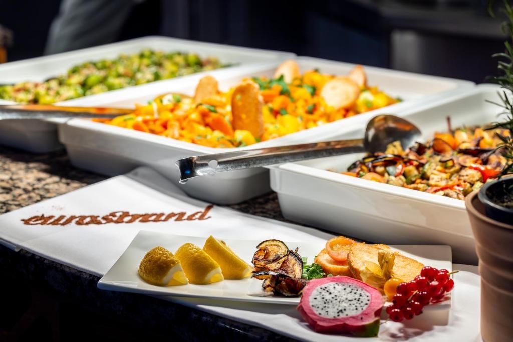 A buffet table with various dishes and a plate with fruit and nuts.