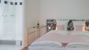 A bedroom with a bed, a bedside table, a nightstand, and a shower area. - Eurostrand Resort Lüneburger Heide (Fintel)