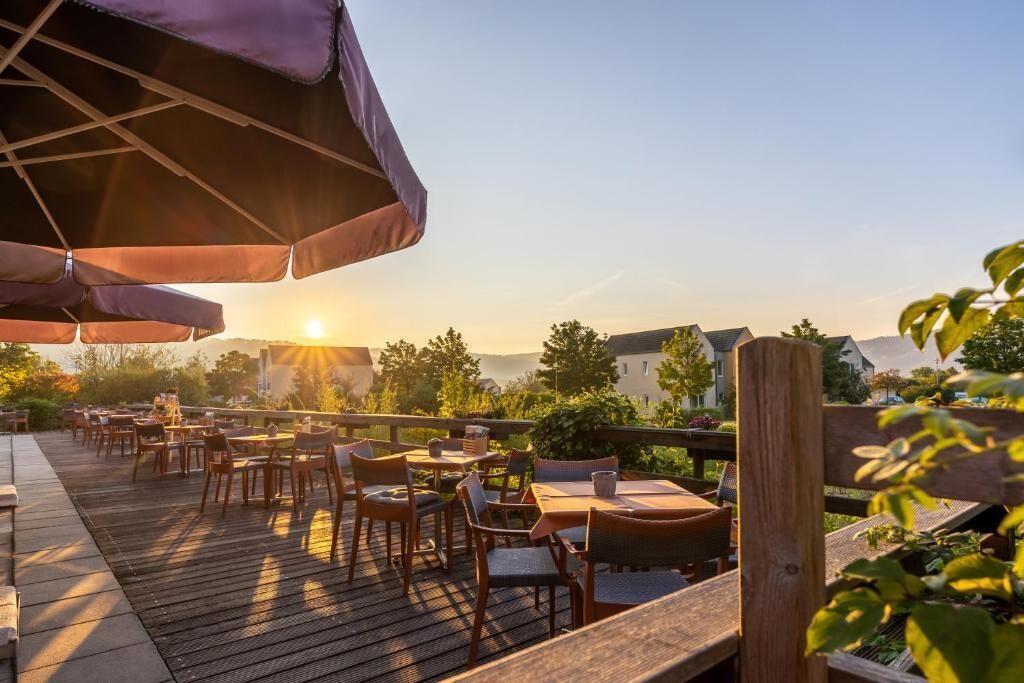 An outdoor dining area with tables and chairs, wooden deck, and umbrellas.