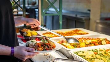 A buffet setup with various dishes, including a plate with a meat dish and a casserole.