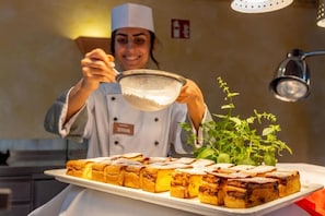 A chef holding a strainer over a tray of food, with a plant in the background. - Eurostrand Resort Moseltal (Leiwen)