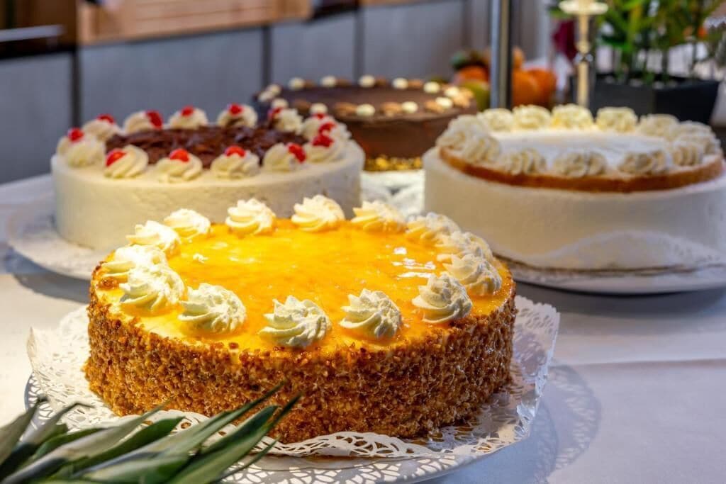 Verschiedene Kuchen auf einem Tisch, darunter eine Spitzendecke.