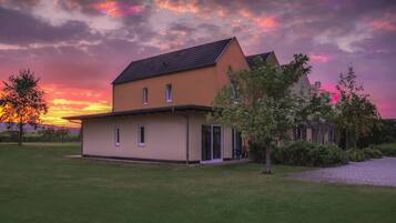 Een modern huis met twee verdiepingen, een plat dak, een klein portaaltje en een verzorgd gazon.