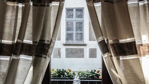A view through sheer curtains to a balcony with potted plants. - Spazio Bianco (Ivrea)