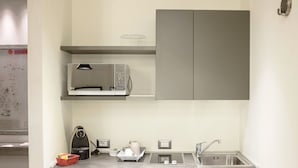 A compact kitchenette with a microwave, kettle, and sink. - Spazio Bianco (Ivrea)